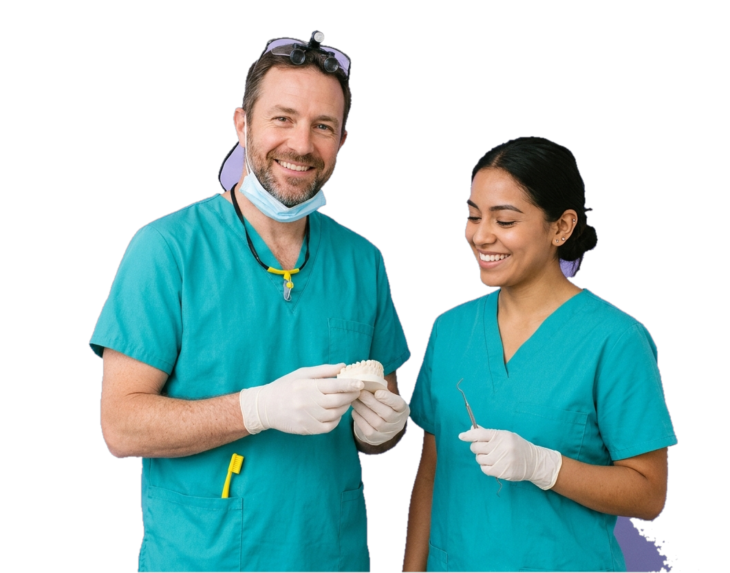 A smiling dentist in teal scrubs holding a dental model of teeth beside a dental assistant holding an instrument, both in a dental practice.