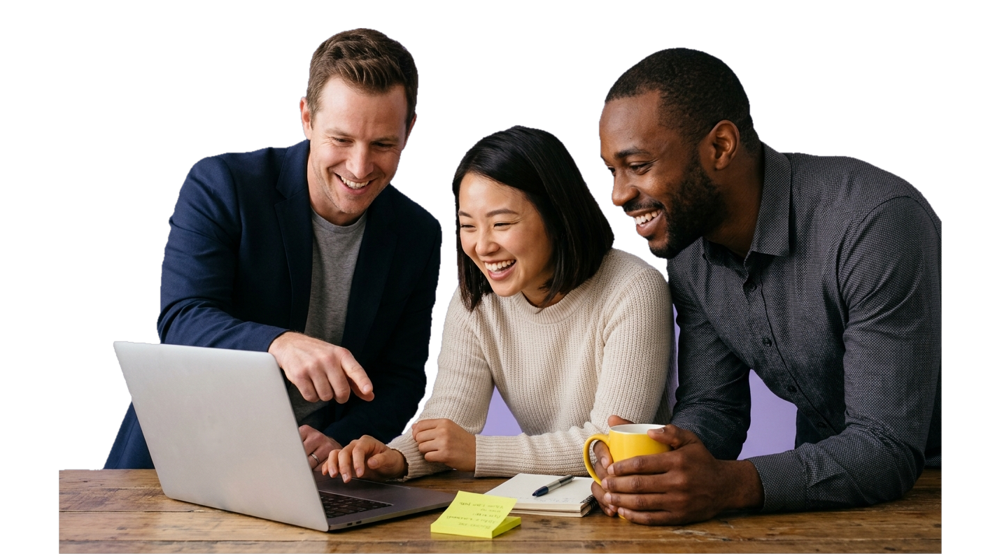 Three colleagues leaning over a laptop at a desk, smiling as one points at the screen, with a yellow mug on the table.